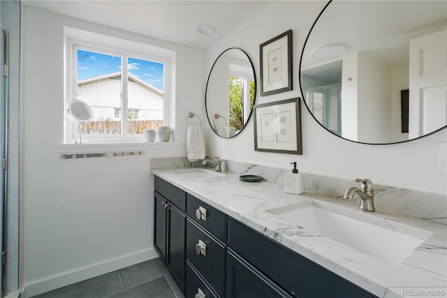 full bathroom featuring baseboards, tile patterned floors, double vanity, and a sink