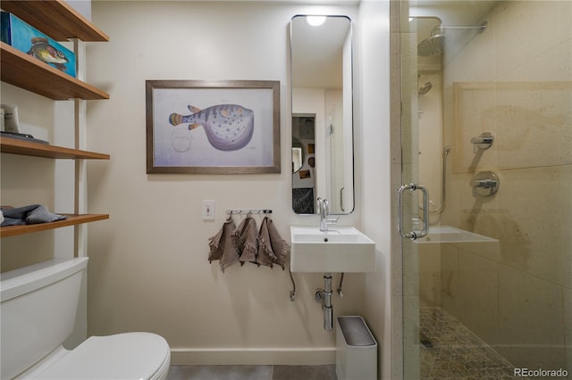 bathroom with toilet, baseboards, and a shower stall
