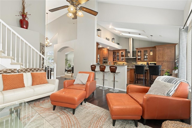 living room featuring hardwood / wood-style floors, ceiling fan with notable chandelier, and high vaulted ceiling