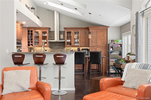 interior space with dark hardwood / wood-style floors, backsplash, hanging light fixtures, kitchen peninsula, and light stone countertops