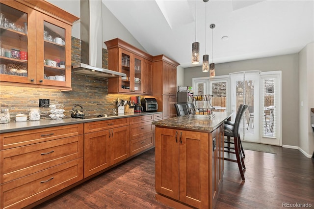 kitchen with a kitchen bar, hanging light fixtures, a center island, black electric cooktop, and wall chimney exhaust hood