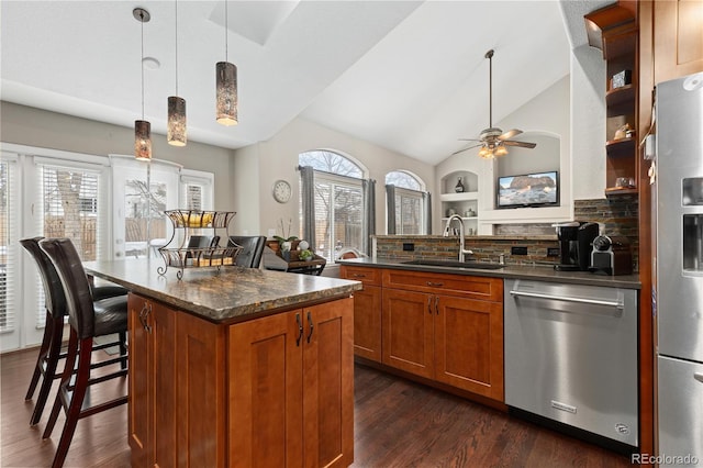 kitchen with sink, a breakfast bar area, a kitchen island, pendant lighting, and stainless steel appliances