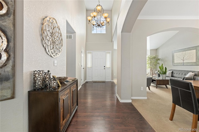 foyer entrance featuring crown molding, a notable chandelier, and dark carpet