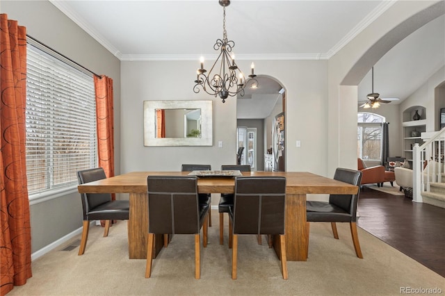 carpeted dining area featuring built in shelves, ornamental molding, and ceiling fan with notable chandelier