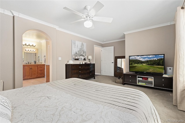 bedroom featuring ceiling fan, ensuite bath, ornamental molding, and light colored carpet