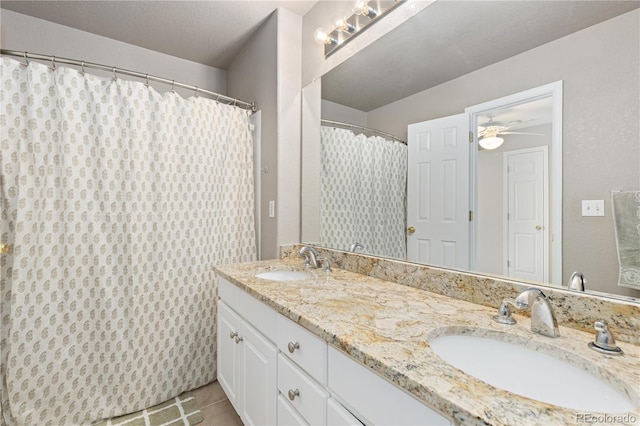 bathroom with tile patterned flooring, vanity, and a textured ceiling