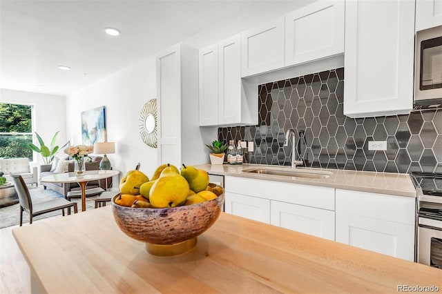 kitchen featuring decorative backsplash, white cabinetry, sink, and stainless steel appliances