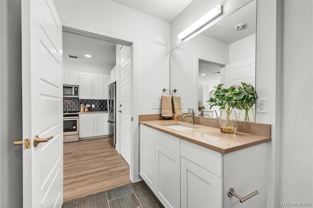 bathroom with decorative backsplash, wood-type flooring, and vanity