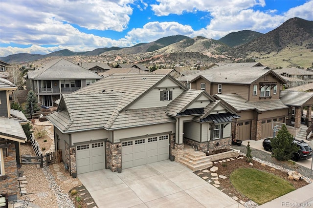 15784 Burrowing Owl Ct, Morrison, CO 80465 - view of front of property featuring stone siding, concrete driveway, a residential view, a mountain view, and a garage