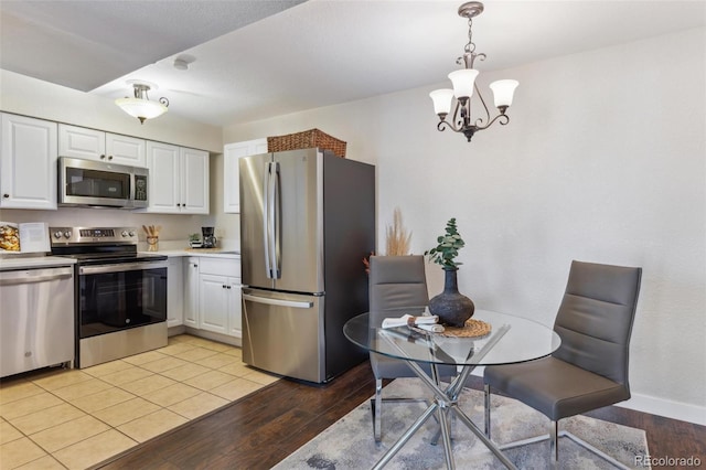 kitchen with a notable chandelier, white cabinetry, decorative light fixtures, stainless steel appliances, and light wood finished floors