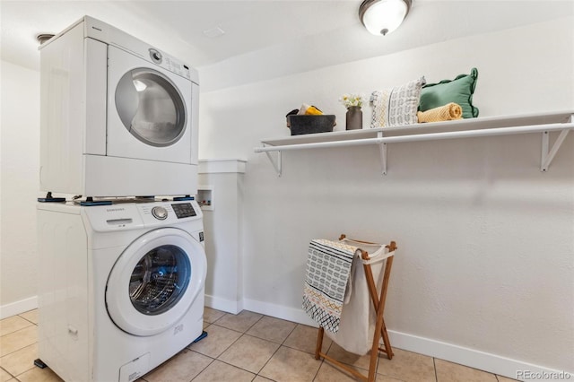 laundry area with baseboards, light tile patterned floors, stacked washer and dryer, and laundry area