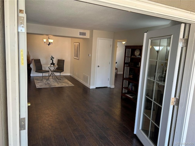 entryway featuring a notable chandelier, dark wood-type flooring, visible vents, and baseboards