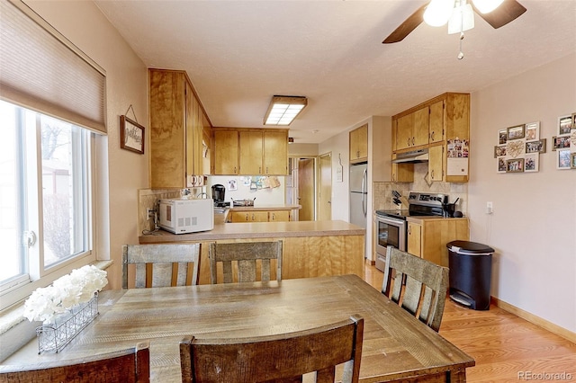 dining area with light wood-style flooring, baseboards, and a ceiling fan