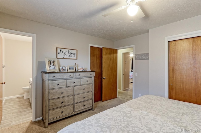 carpeted bedroom with baseboards, a ceiling fan, ensuite bath, a textured ceiling, and a closet