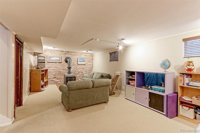 living room with carpet floors, visible vents, a wood stove, a textured ceiling, and brick wall