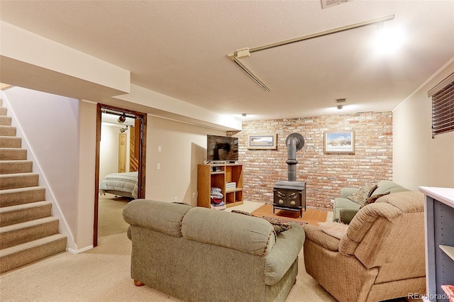 living area featuring light carpet, brick wall, stairway, and a wood stove