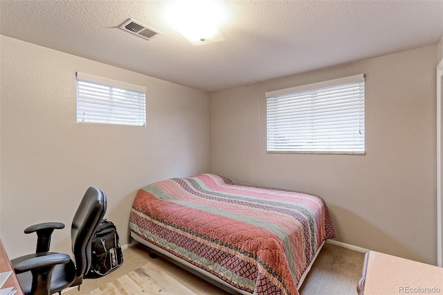 carpeted bedroom featuring visible vents, a textured ceiling, and baseboards