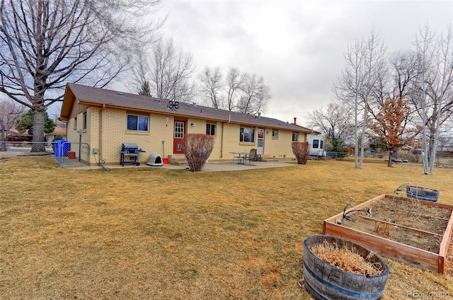 rear view of house featuring a garden, fence, a yard, a patio area, and brick siding