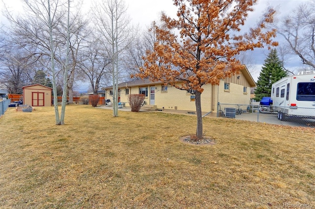 view of yard featuring central AC unit, a fenced backyard, a storage unit, and an outdoor structure