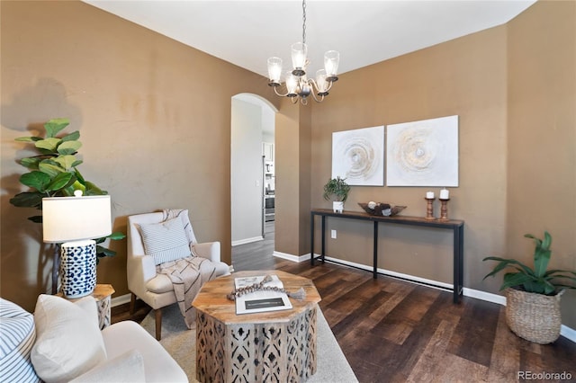 sitting room with an inviting chandelier, baseboards, arched walkways, and wood finished floors