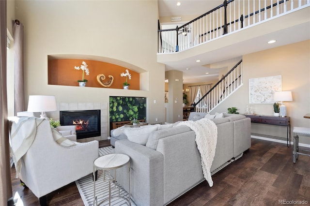 living room with recessed lighting, a fireplace, a towering ceiling, stairway, and dark wood finished floors