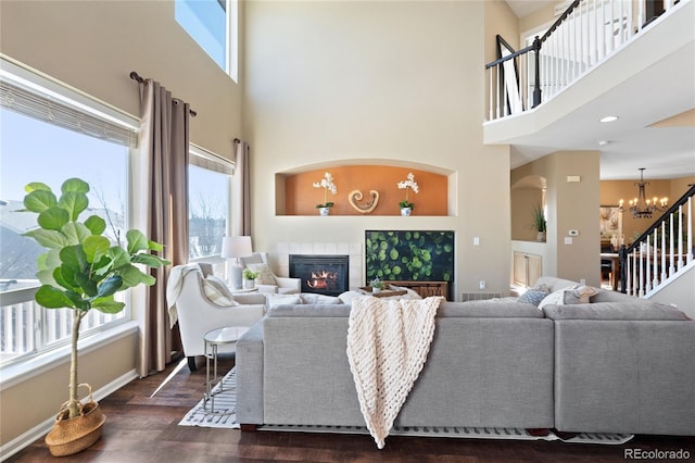 living area featuring dark wood-style flooring, visible vents, stairway, an inviting chandelier, and a tile fireplace