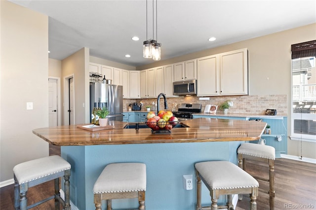 kitchen featuring tasteful backsplash, butcher block countertops, appliances with stainless steel finishes, dark wood-type flooring, and decorative light fixtures