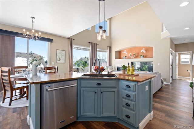 kitchen with an inviting chandelier, open floor plan, a kitchen island with sink, a sink, and dishwasher