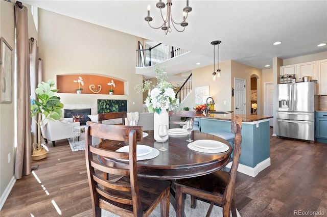 dining area featuring dark wood-type flooring, arched walkways, a glass covered fireplace, and an inviting chandelier