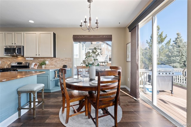 dining area featuring dark wood-style floors, baseboards, and an inviting chandelier