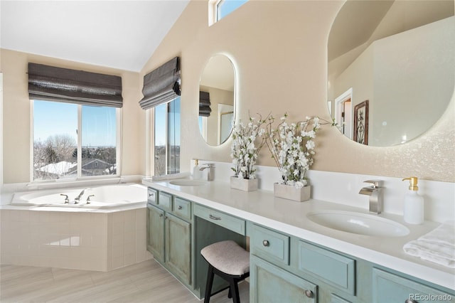 bathroom featuring lofted ceiling, a garden tub, double vanity, and a sink