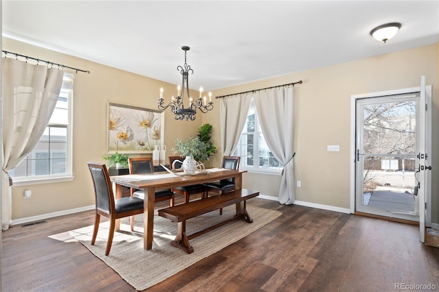 dining area featuring dark wood-type flooring, a chandelier, visible vents, and baseboards