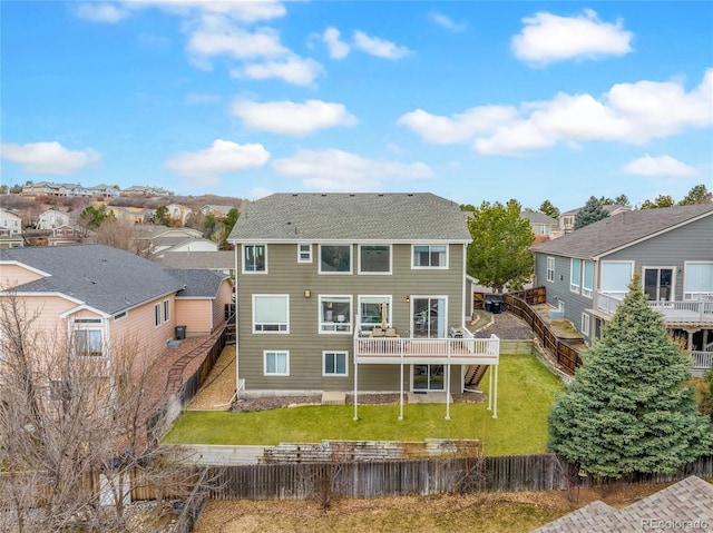 back of house featuring a residential view, a fenced backyard, a lawn, and a wooden deck