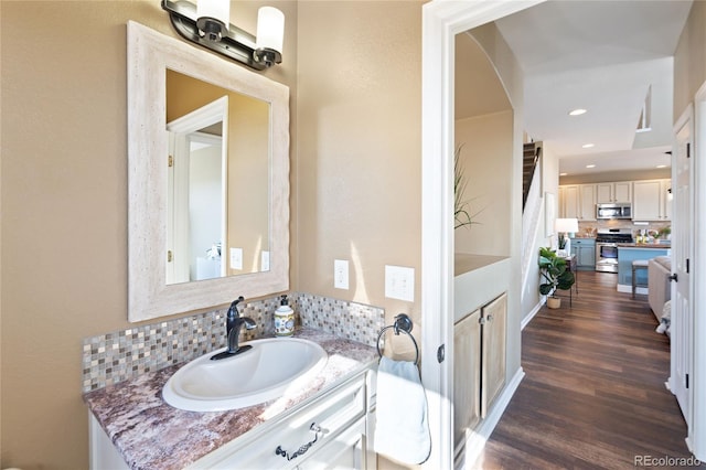 bathroom featuring recessed lighting, wood finished floors, vanity, and decorative backsplash