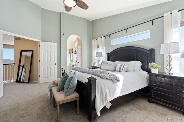 carpeted bedroom featuring arched walkways, high vaulted ceiling, ceiling fan, and visible vents