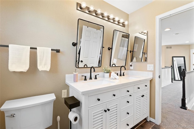 full bathroom featuring toilet, double vanity, visible vents, and a sink