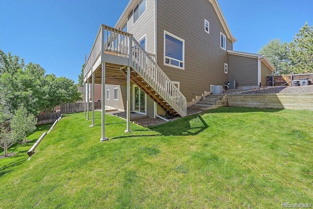 rear view of house featuring a deck, a lawn, stairway, and fence