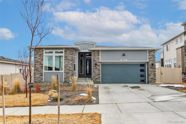 prairie-style home featuring stucco siding, concrete driveway, fence, a garage, and stone siding