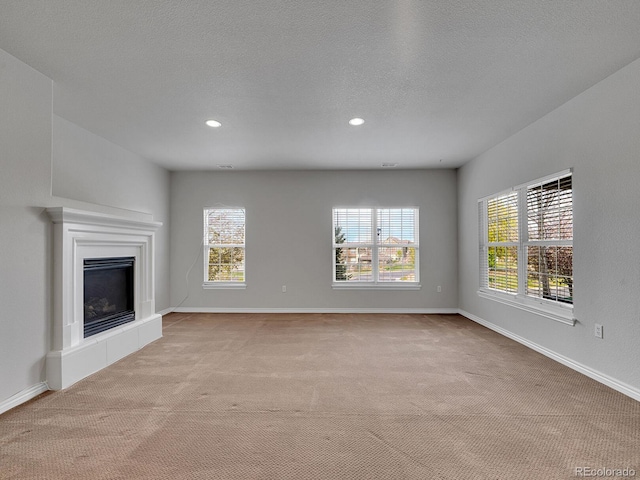 unfurnished living room featuring plenty of natural light, recessed lighting, and carpet