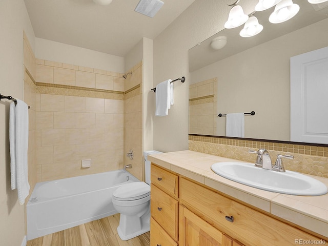 bathroom featuring visible vents, wood finished floors, vanity, toilet, and  shower combination