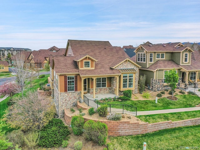 view of front of home with a fenced backyard, a residential view, a patio area, and stone siding