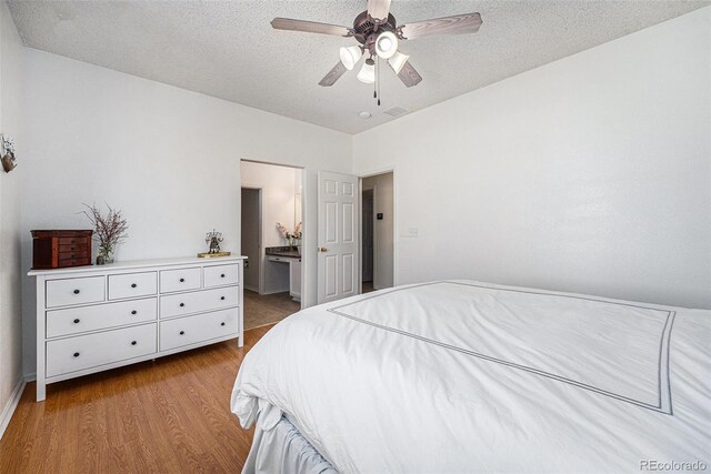 20137 E Prentice Pl, Centennial, CO 80015 - bedroom featuring a textured ceiling, ceiling fan, ensuite bathroom, and wood finished floors
