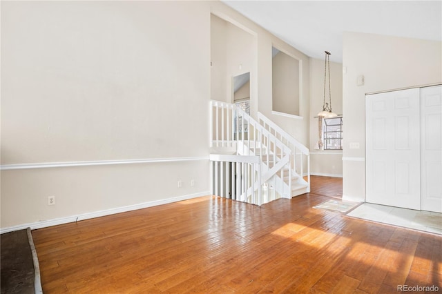 spare room with wood-type flooring and high vaulted ceiling