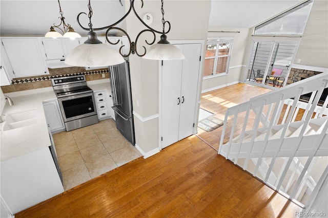 kitchen featuring pendant lighting, white cabinetry, light hardwood / wood-style floors, sink, and stainless steel electric range oven