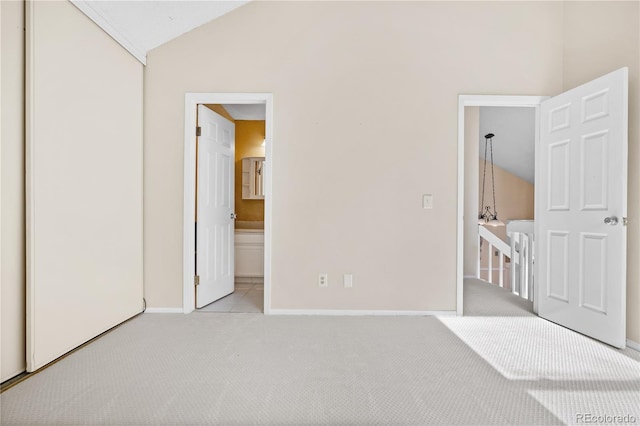 unfurnished bedroom with light colored carpet, connected bathroom, and vaulted ceiling