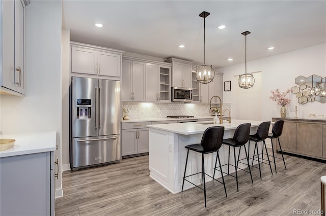 431 Courtfield Way, Castle Pines, CO 80108 - kitchen featuring stainless steel appliances, decorative backsplash, a breakfast bar, light wood finished floors, and recessed lighting