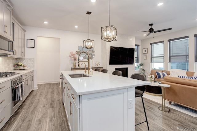431 Courtfield Way, Castle Pines, CO 80108 - kitchen with appliances with stainless steel finishes, a breakfast bar area, open floor plan, light wood-type flooring, and light countertops