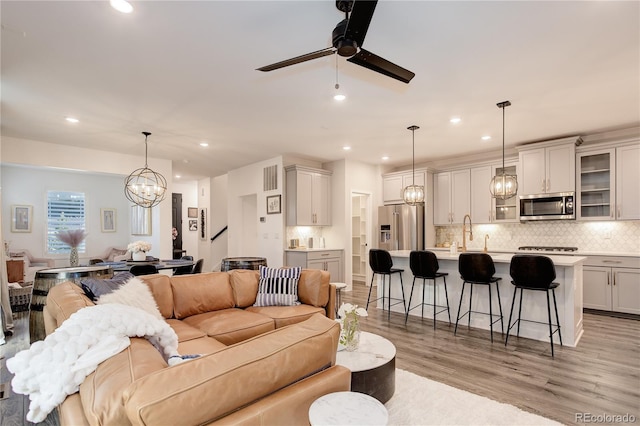 431 Courtfield Way, Castle Pines, CO 80108 - living area with ceiling fan, light wood finished floors, a chandelier, recessed lighting, and stairway
