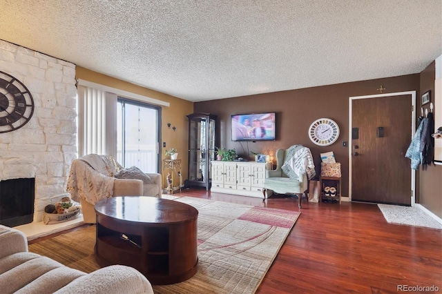 living area with a fireplace, baseboards, wood finished floors, and a textured ceiling