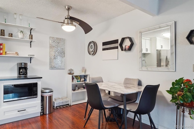 dining space with a textured ceiling, dark wood-style flooring, and a ceiling fan